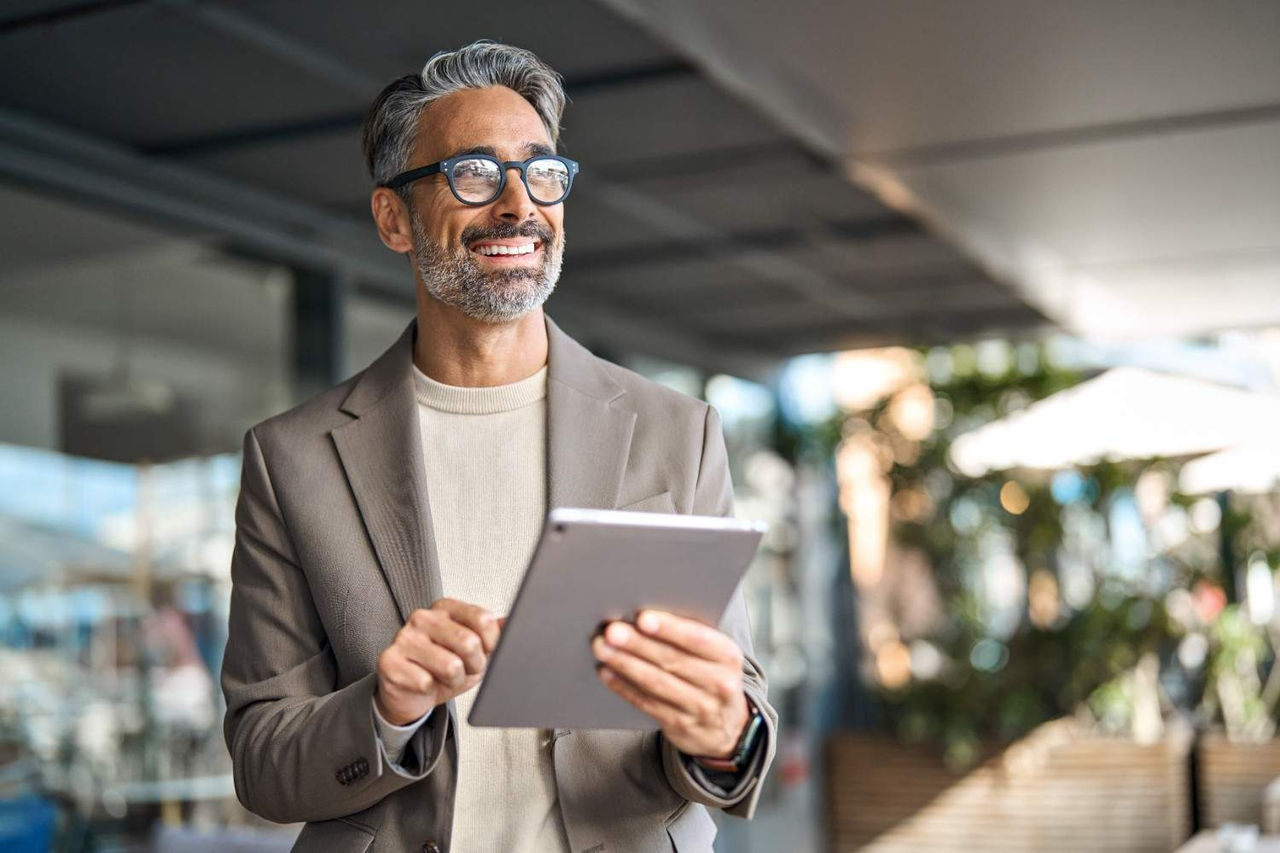 Homem adulto sorrindo com um computador nas mãos