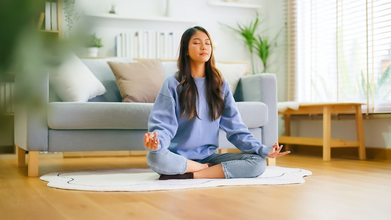 Mulher meditando na sala de casa